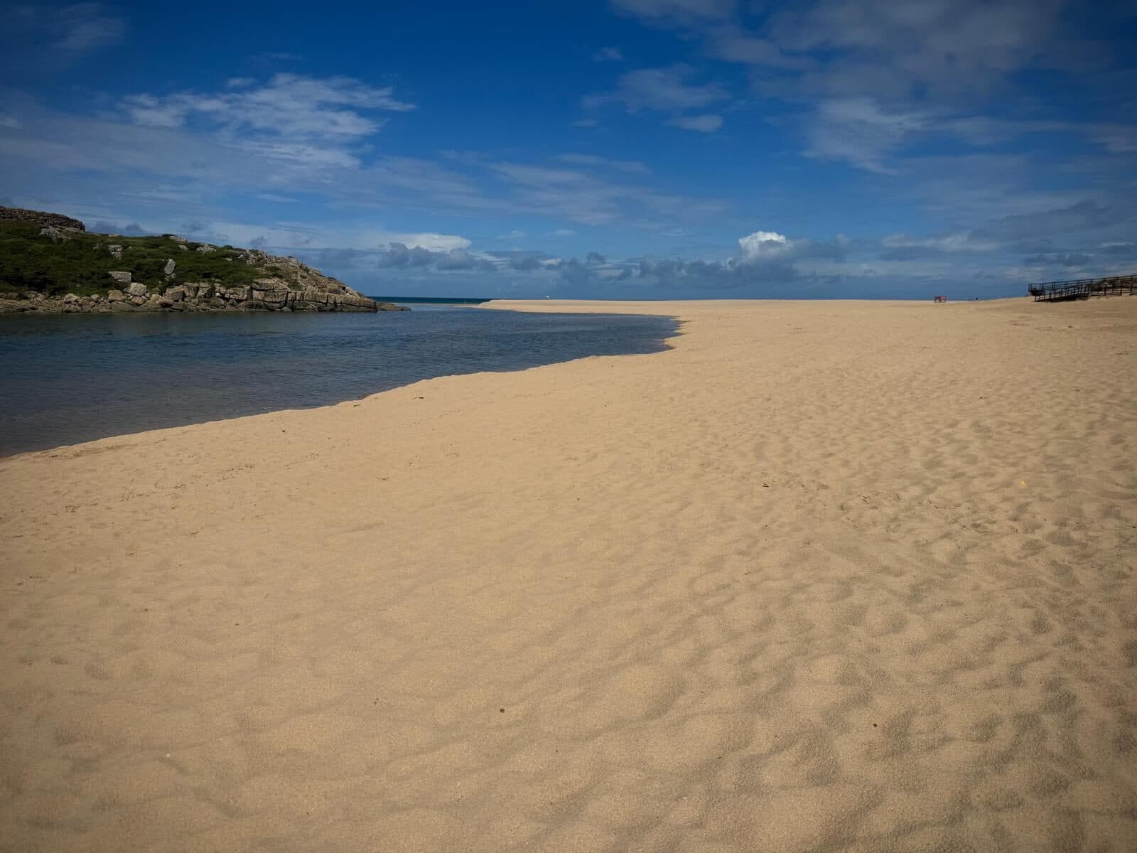Empty sand and the calm river mouth at Foz do Lizandro beach, Ericeira